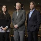 Three people are standing in an empty auditorium.